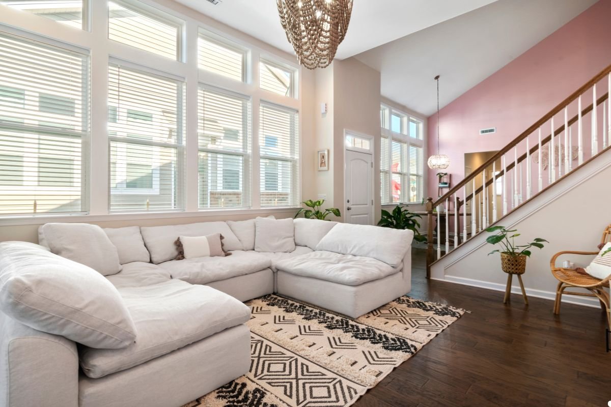 A cozy living room featuring a white couch against a soft pink wall, creating a warm and inviting atmosphere. 